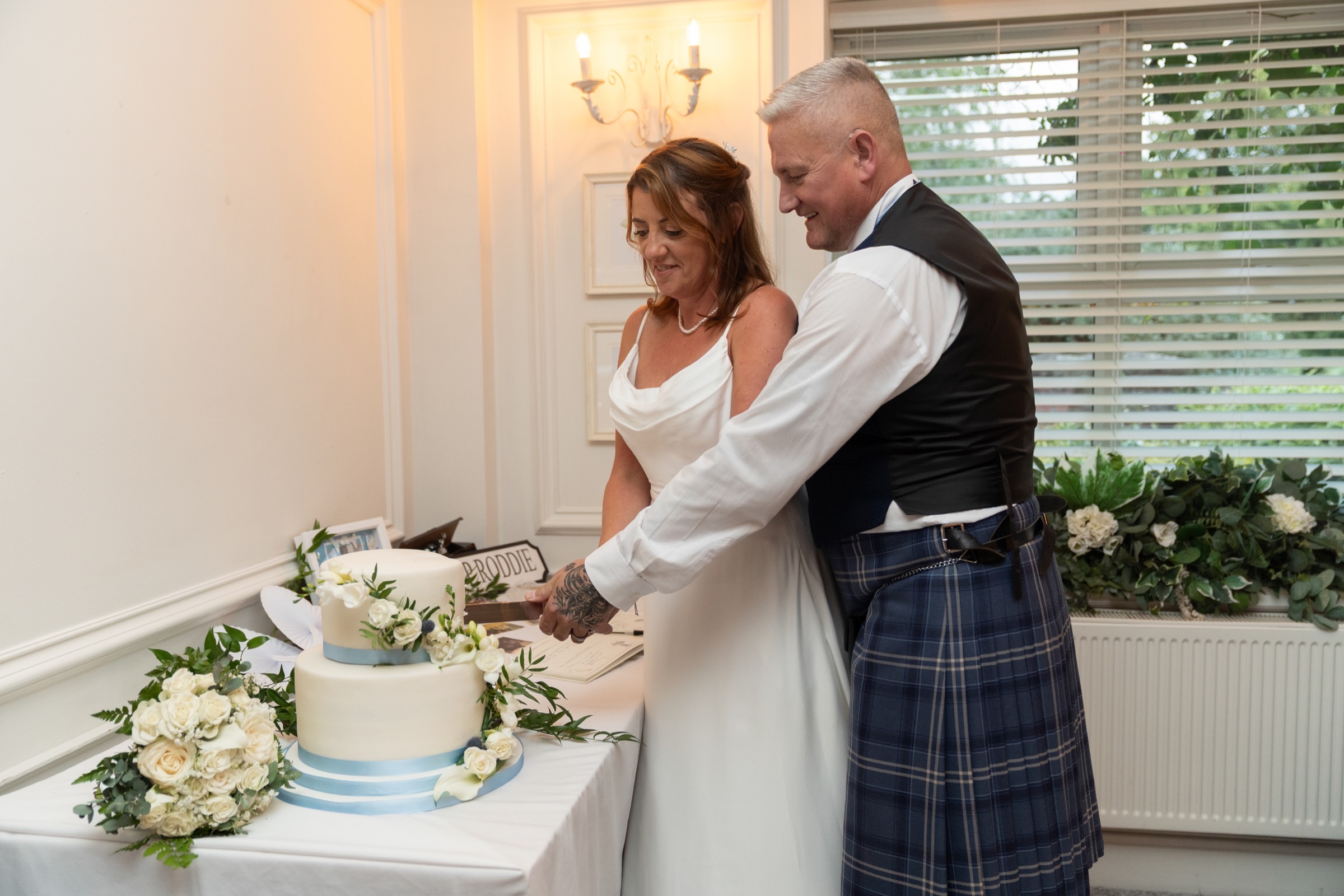 Couple cutting their wedding cake together — natural, relaxed, not performed