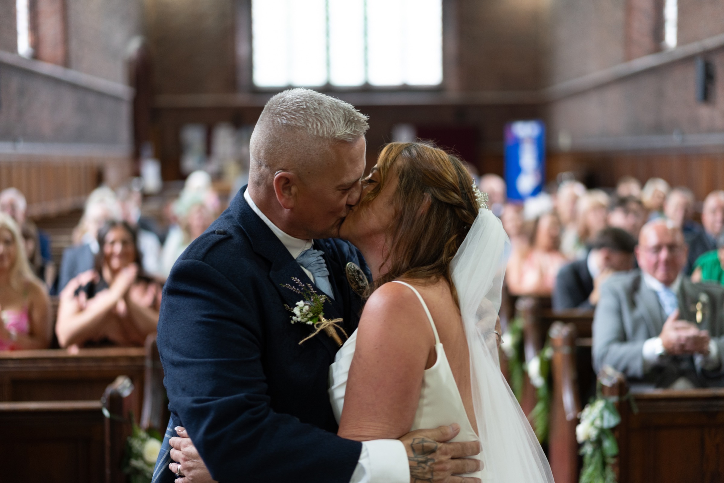 The first kiss — couple kissing at the church altar as guests applaud around them